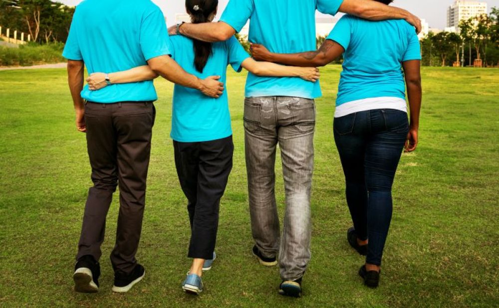A group of volunteers walking arm in arm through a park