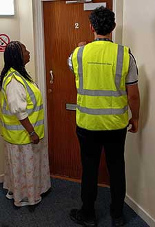 2 people in high vis jackets knocking on a door