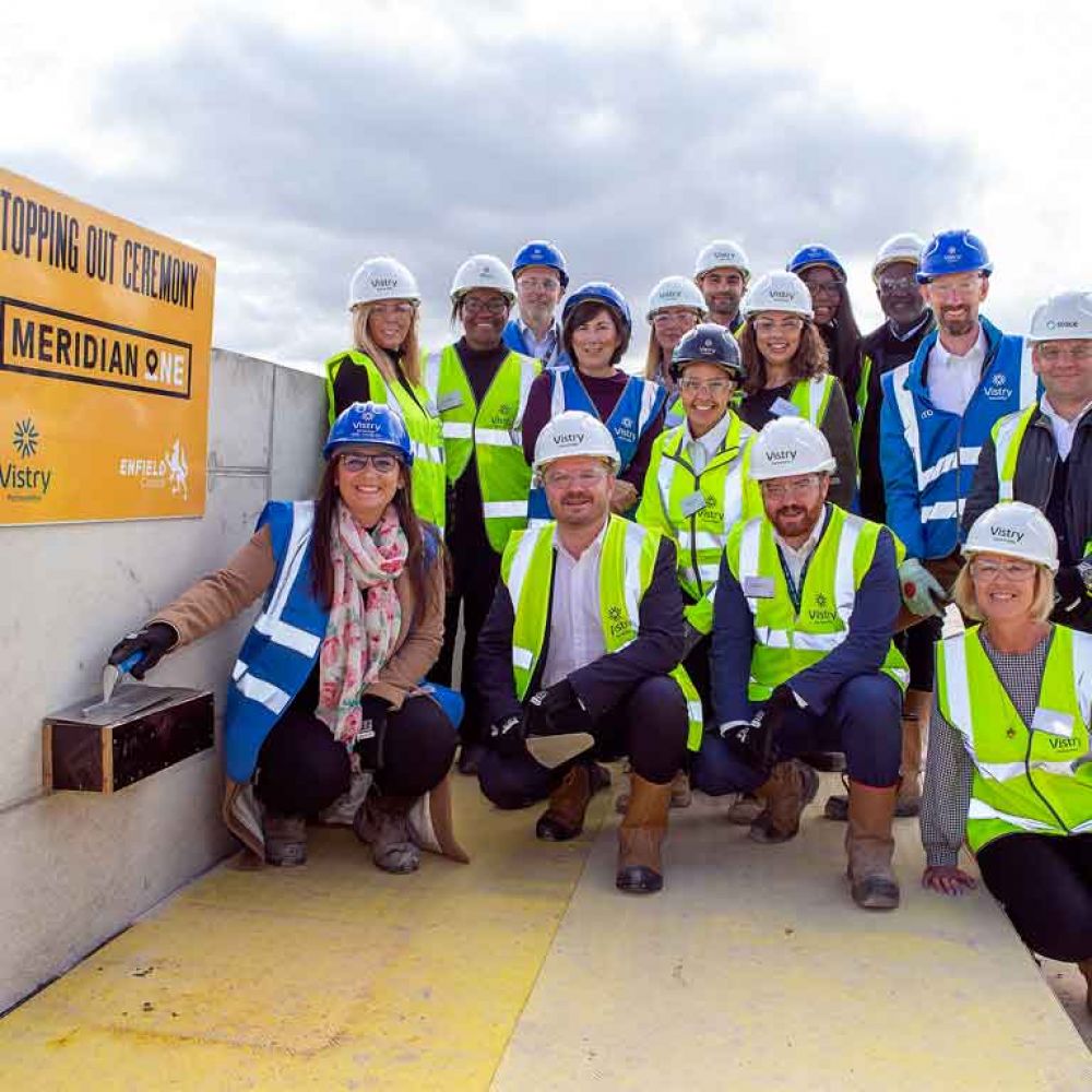 Topping out ceremony on top of building with group in hard hards and high visibility vests