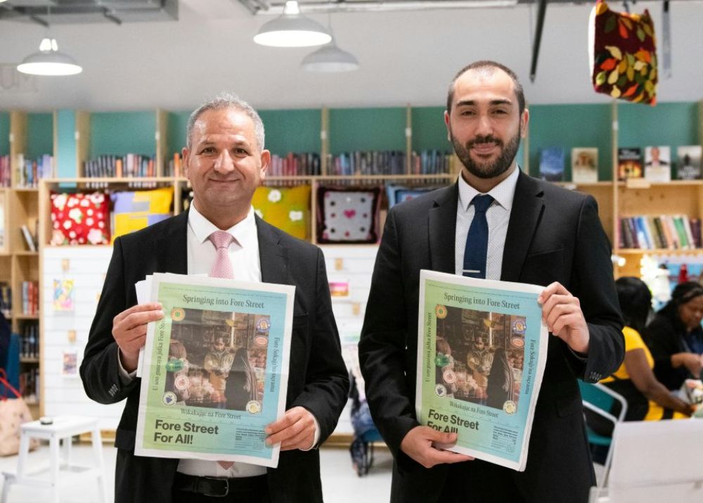 Councillor Ozaydin and Cllr Erbil hold up a newspaper created by Fore Street For All at the Fore Street Library