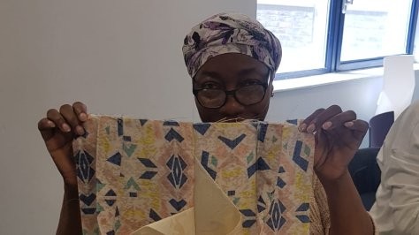Grace holding up her sewing at her workshop