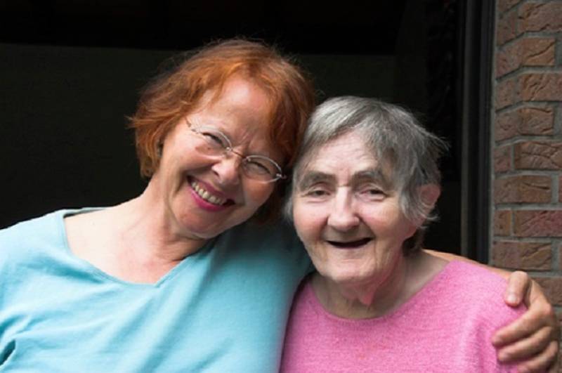 Two people standing with arms around each other