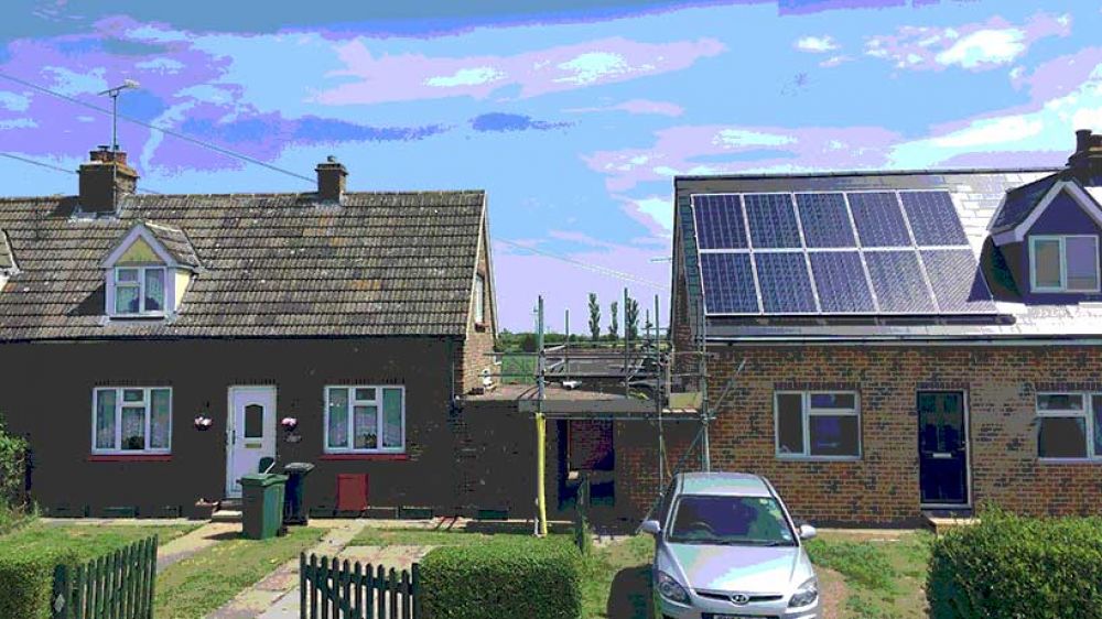 Two residential homes, both undergoing works including installation of solar panels. Scaffolding leans against one of  the homes.