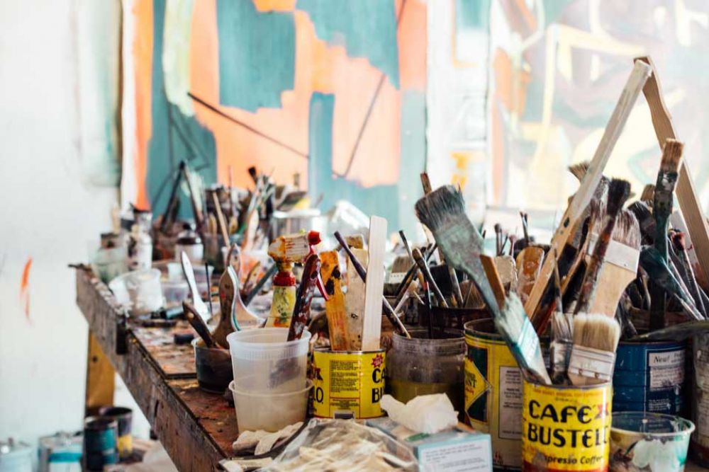 A table filled with pots of paint brushes and other art tools