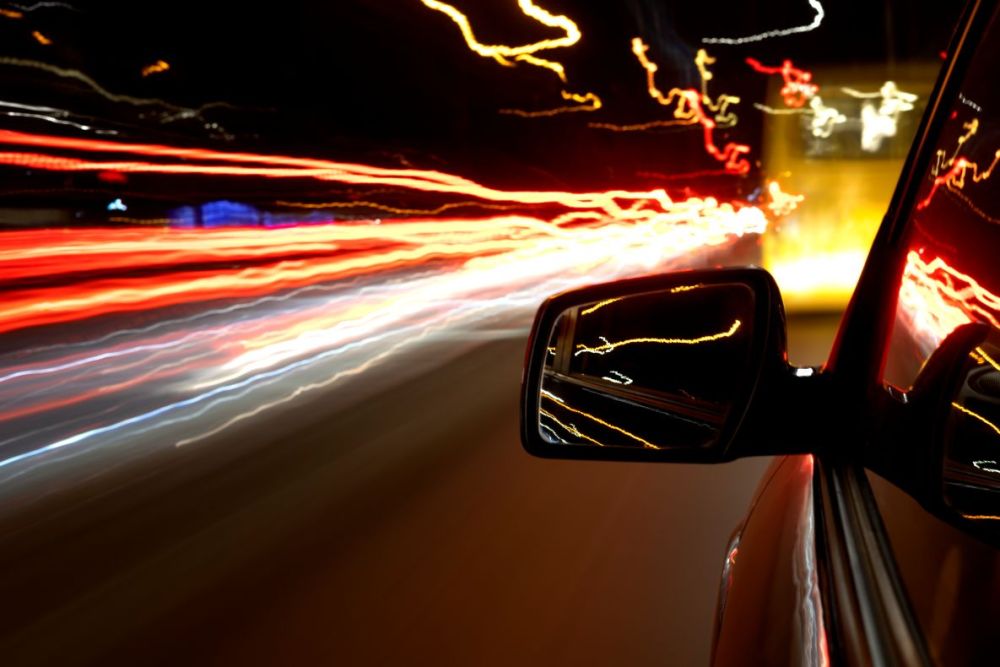 Speeding car at night surrounded by city lights