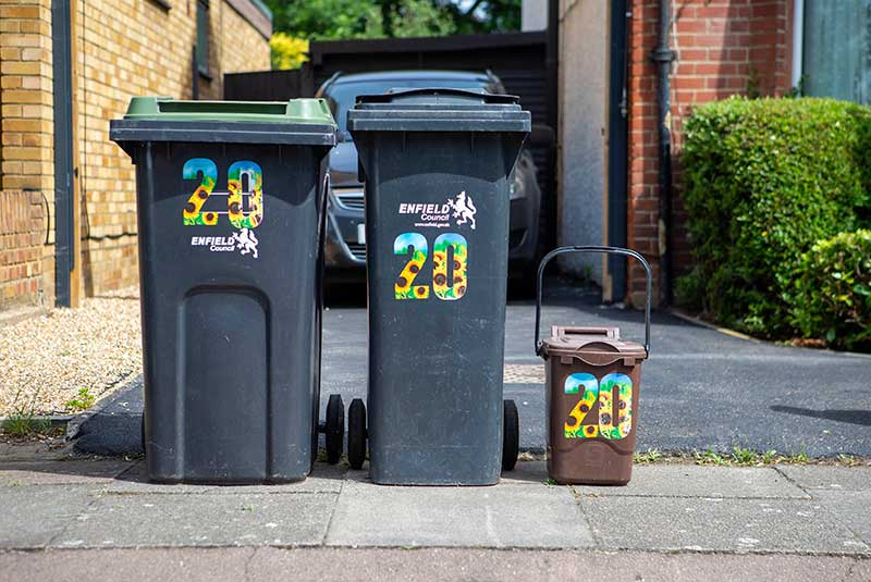 Black rubbish bin, green garden waste bin and brown food waste bin outside a house