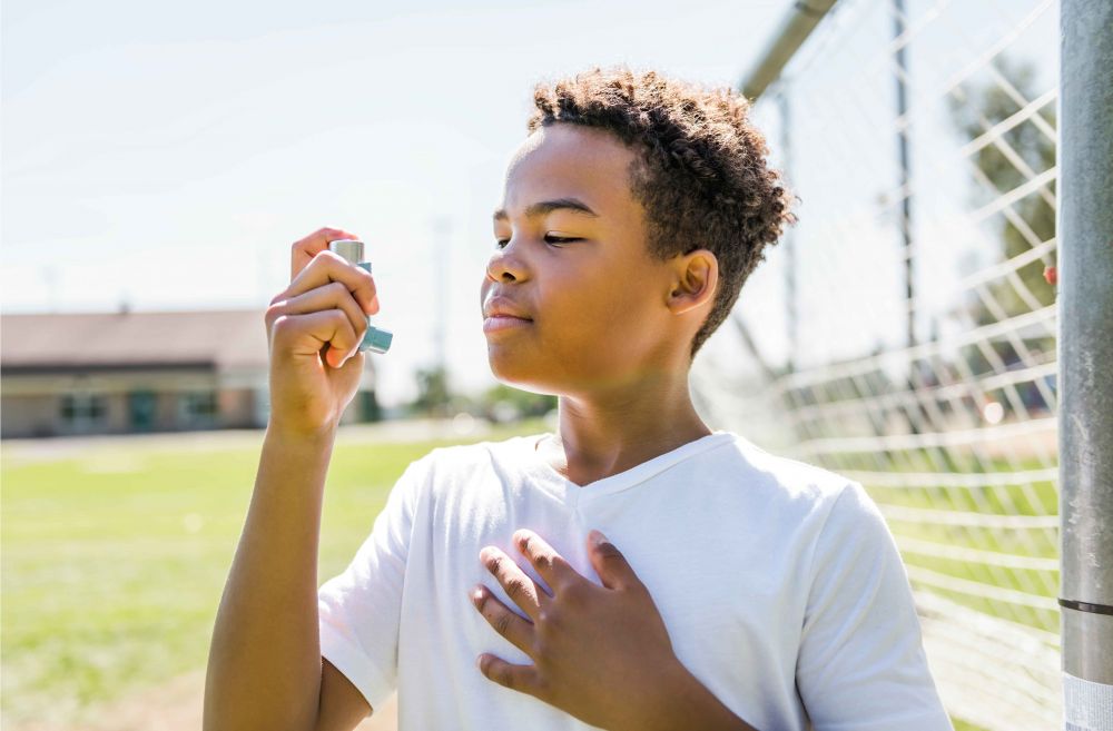 A boy holding an asthma inhaler. 