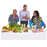 3 people standing behind a table of healthy food