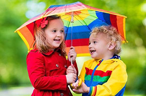 Two young children holding an umbrella