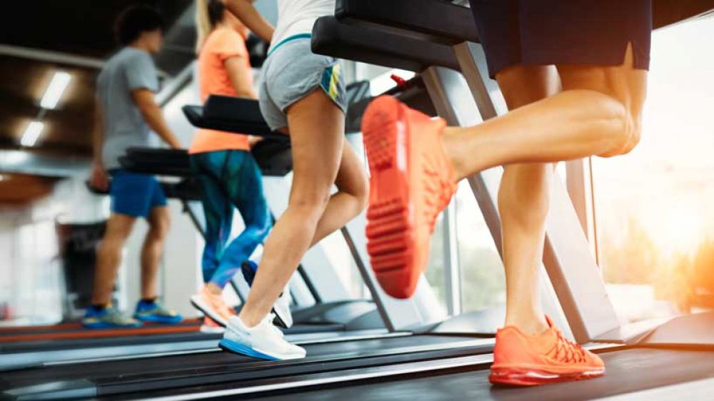Runners on treadmills in a gym. Fee and legs shown.