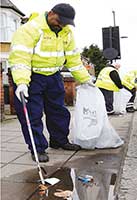 Man in high-vis jacket picking up litter on the street