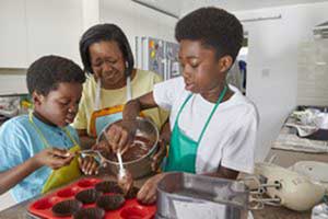Two children making cakes with their parent