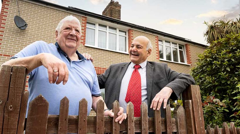 Cllr Savva leans against a gate with resident David