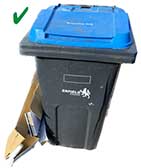 Green tick next to blue recycling bin with cardboard at the side