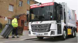 Man in high-vis jacket pulling a rubbish bin towards a bin lorry
