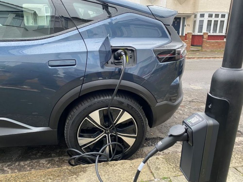 An electric vehicle being charged by lead into a lamppost