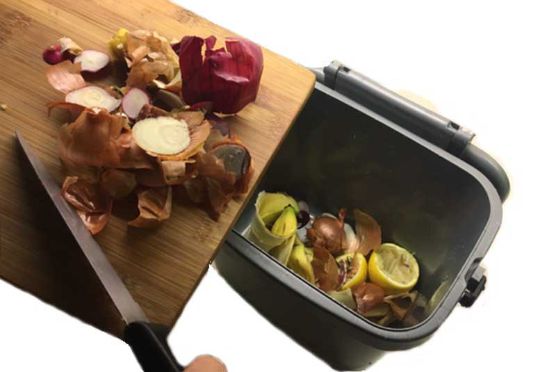 Food waste being scrapped into a kitchen caddy