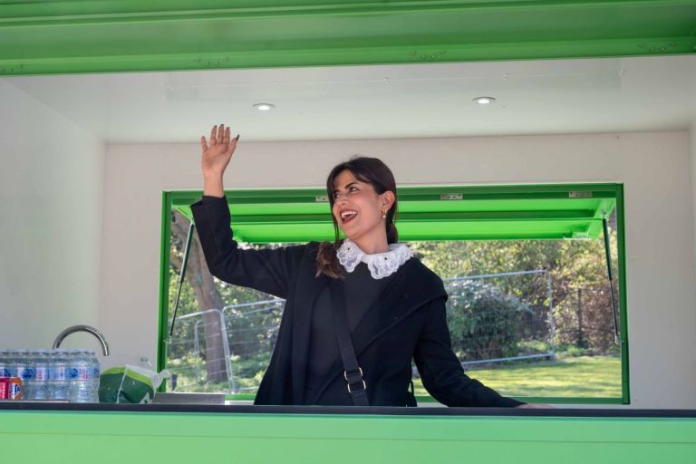 Business Owner at Edmonton Green Pop-Up in a kiosk, waving