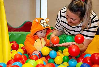 Mum with toddler sitting in a ball pit