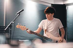 Teenager playing a guitar in a studio