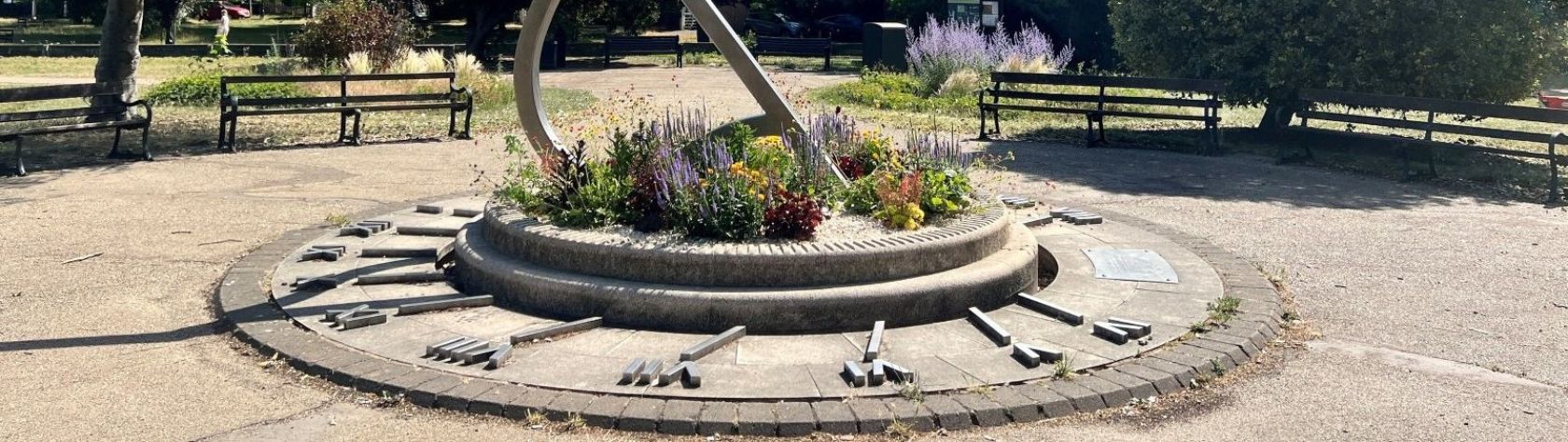 Sundial in Enfield Town surrounded by plants and flowers and benches